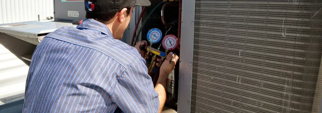 HVAC technician servicing a condenser unit in Atlanta